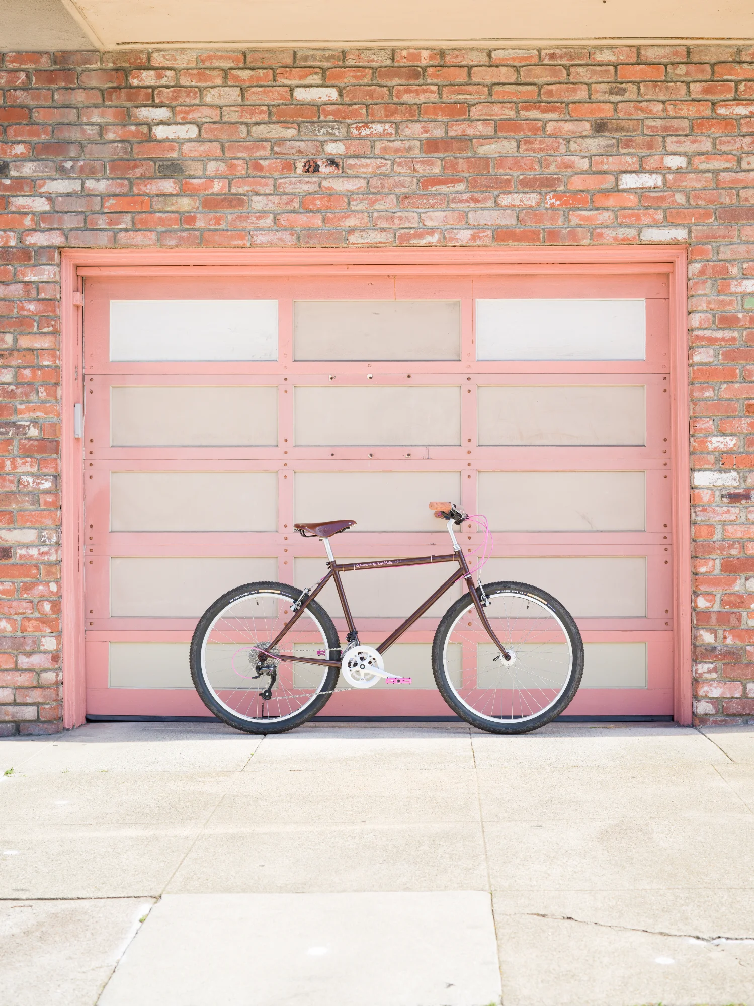 Brown bike against pink garage